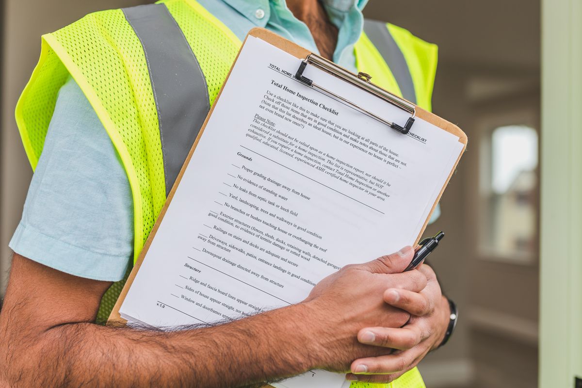 Professionnel tenant une liste de contrôle d’inspection lors de la visite d’un logement avant achat