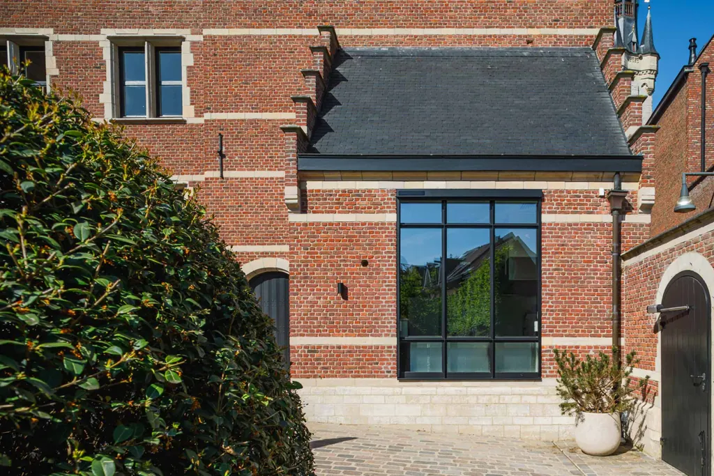 Châssis en acier dans la partie historique en brique d'une maison rénovée à Lierre